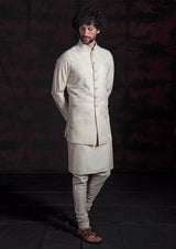Beige embroidered long nehru jacket with beige kurta and chooridar.
