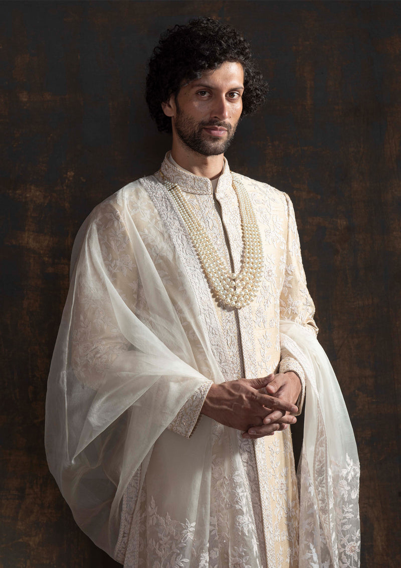 Champagne coloured raw silk sherwani with ivory thread embroidery all over.  Paired up with off white kurta pajama and a stole made in organza with the sherwani's embroidery on it.