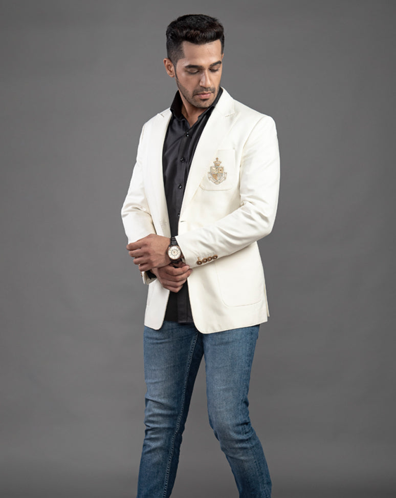 White cotton blazer with peak lapel and embroidered motif on the pocket.