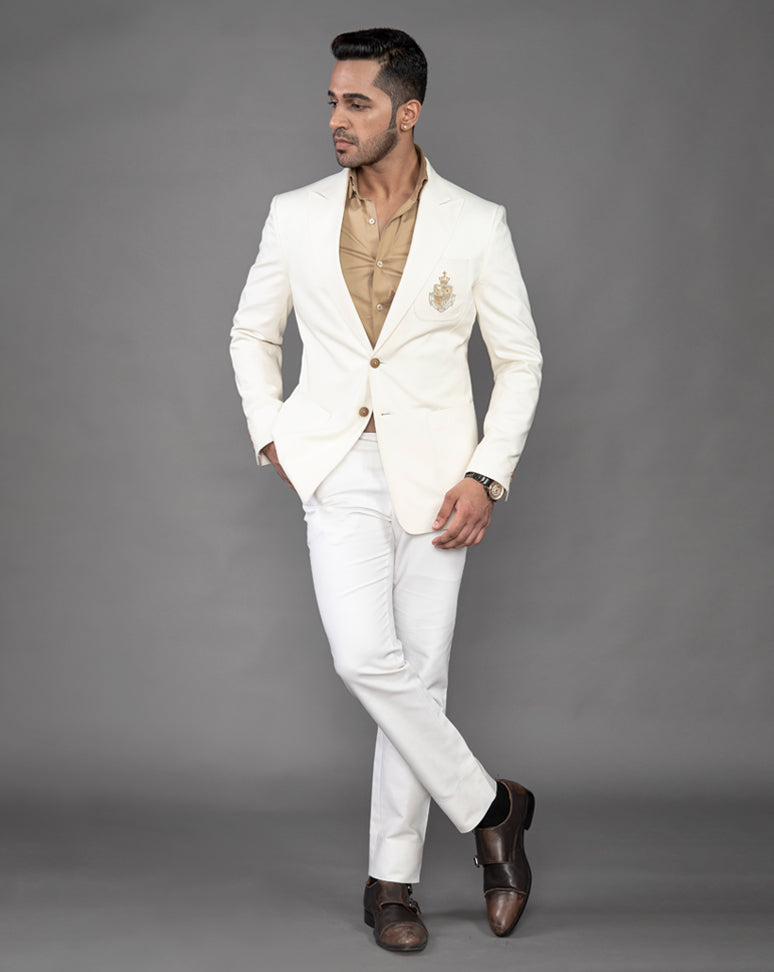 White cotton blazer with peak lapel and embroidered motif on the pocket.
