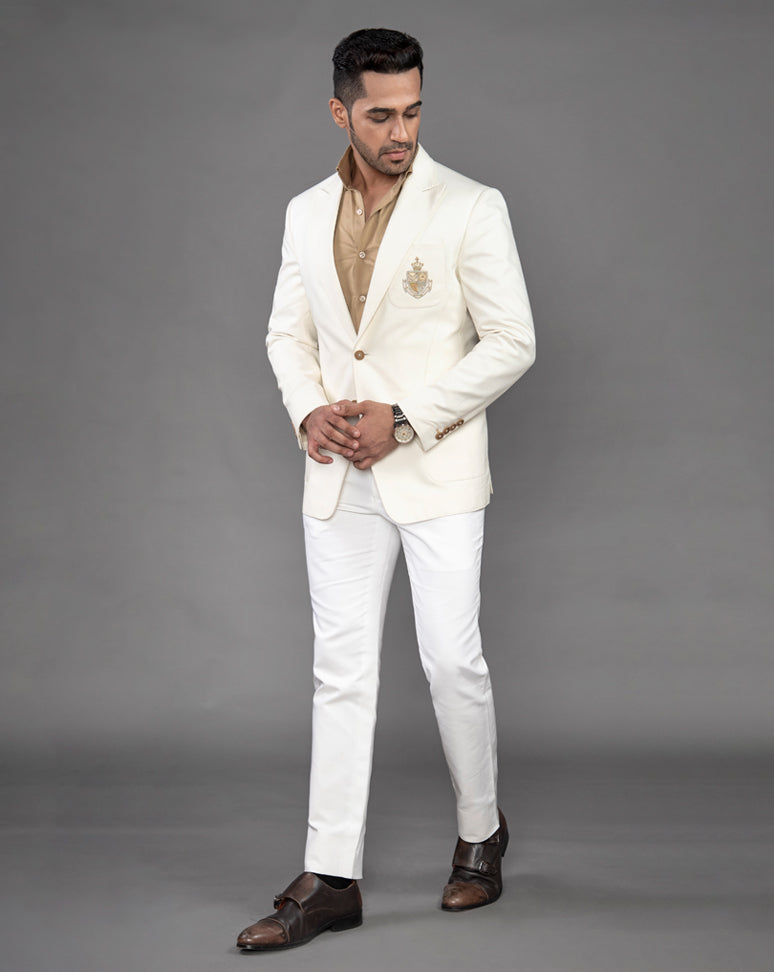 White cotton blazer with peak lapel and embroidered motif on the pocket.