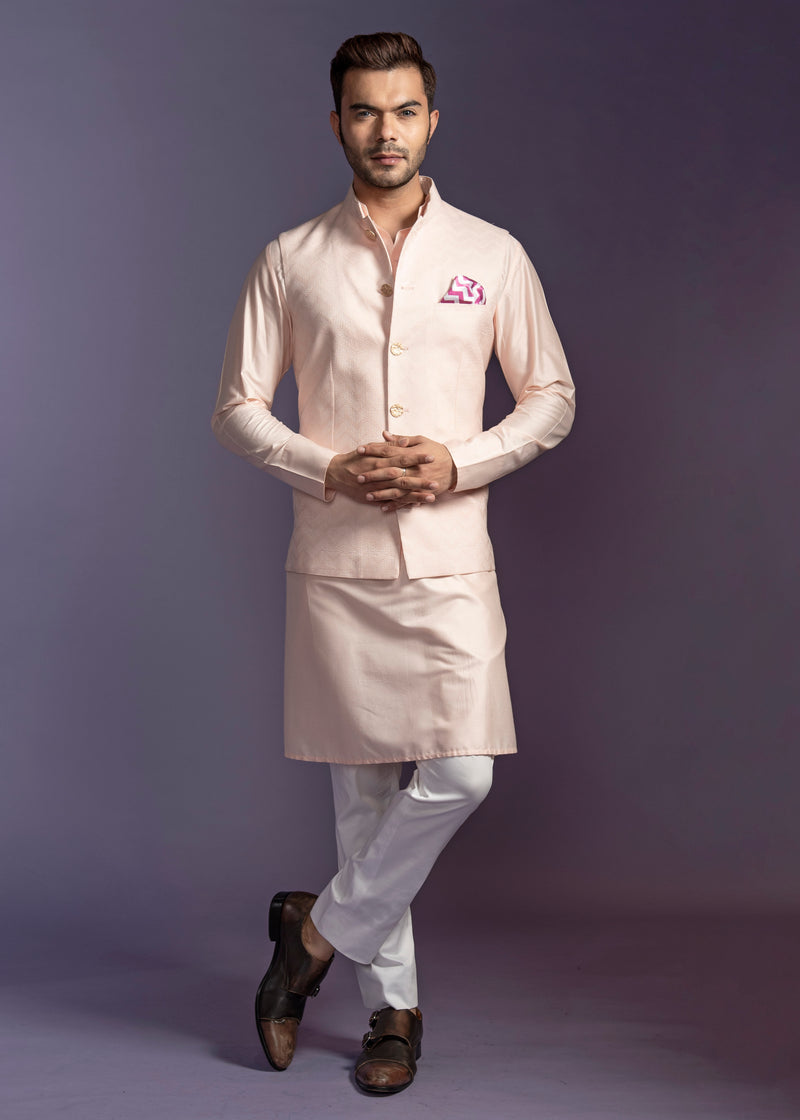 Peach nehru jacket with peach kurta and off white pant pajama.