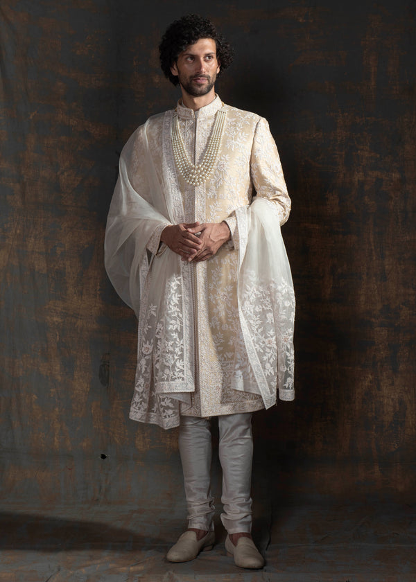 Champagne coloured raw silk sherwani with ivory thread embroidery all over.  Paired up with off white kurta pajama and a stole made in organza with the sherwani's embroidery on it.