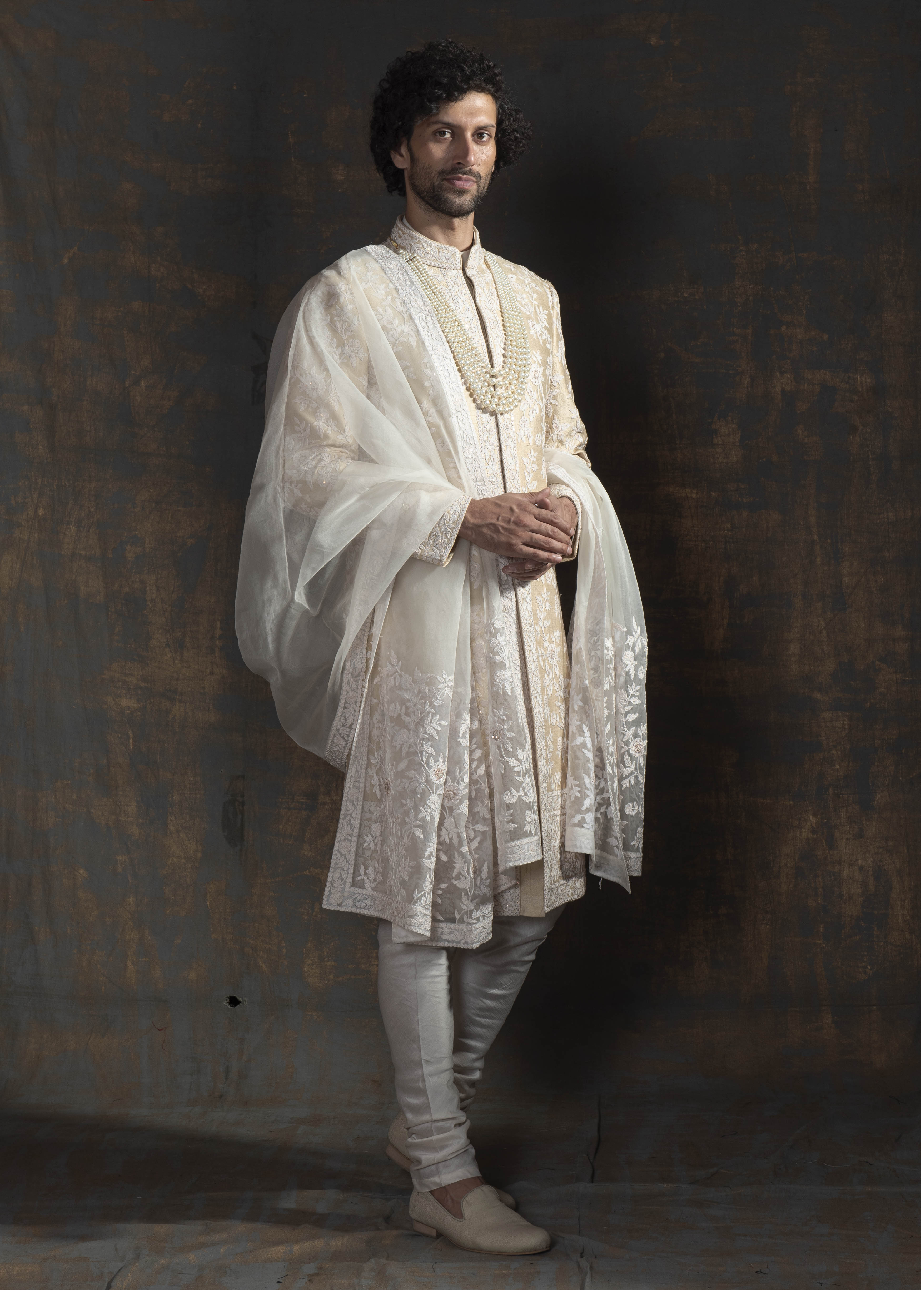 Champagne coloured raw silk sherwani with ivory thread embroidery all over.  Paired up with off white kurta pajama and a stole made in organza with the sherwani's embroidery on it.