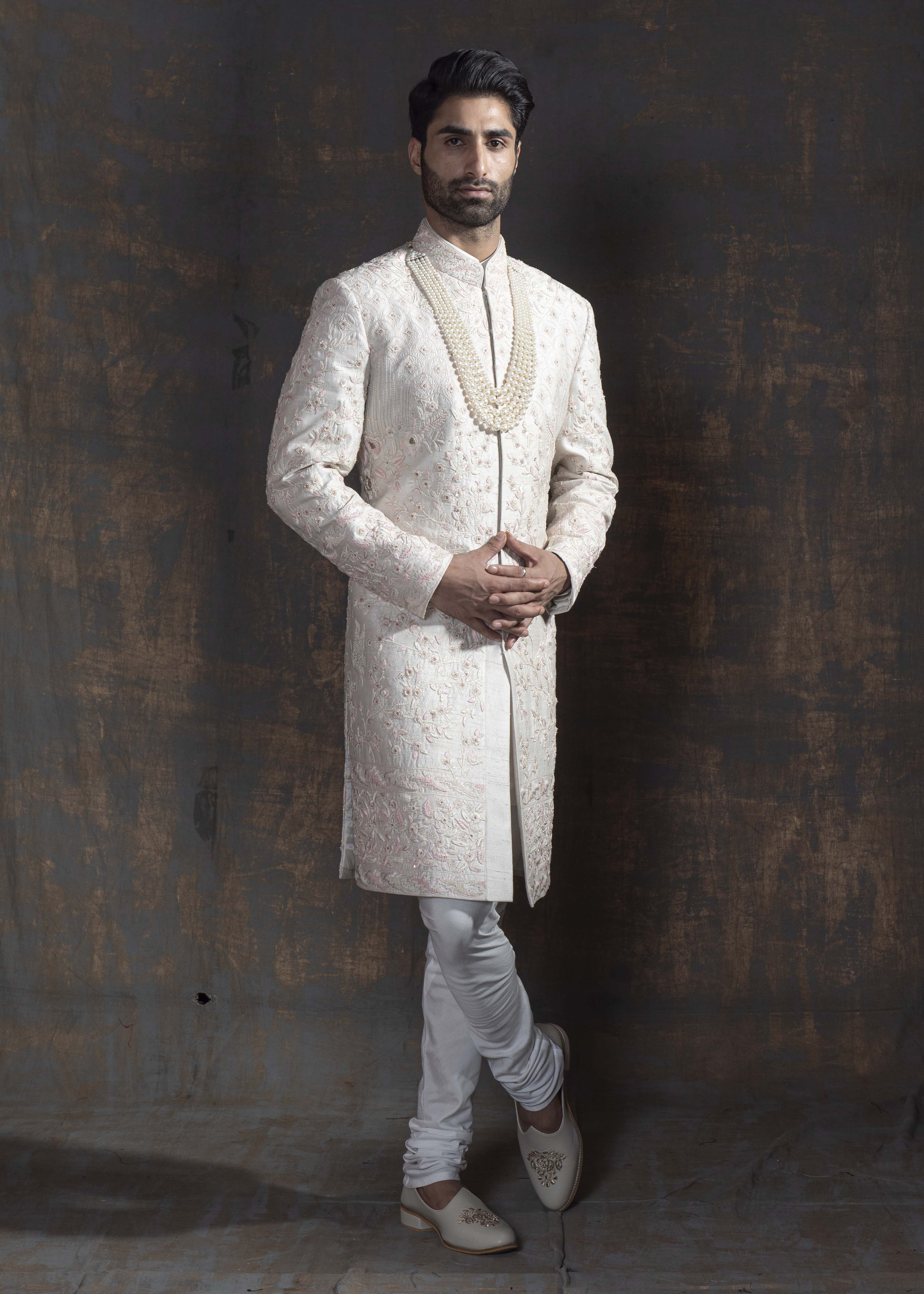 Ivory raw silk sherwani with all over light pink coloured hand embroidery. Paired up with off white kurta and chooridaar and an ivory stole with the sherwani's embroidery as the border.