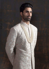Ivory raw silk sherwani with all over light pink coloured hand embroidery. Paired up with off white kurta and chooridaar and an ivory stole with the sherwani's embroidery as the border.
