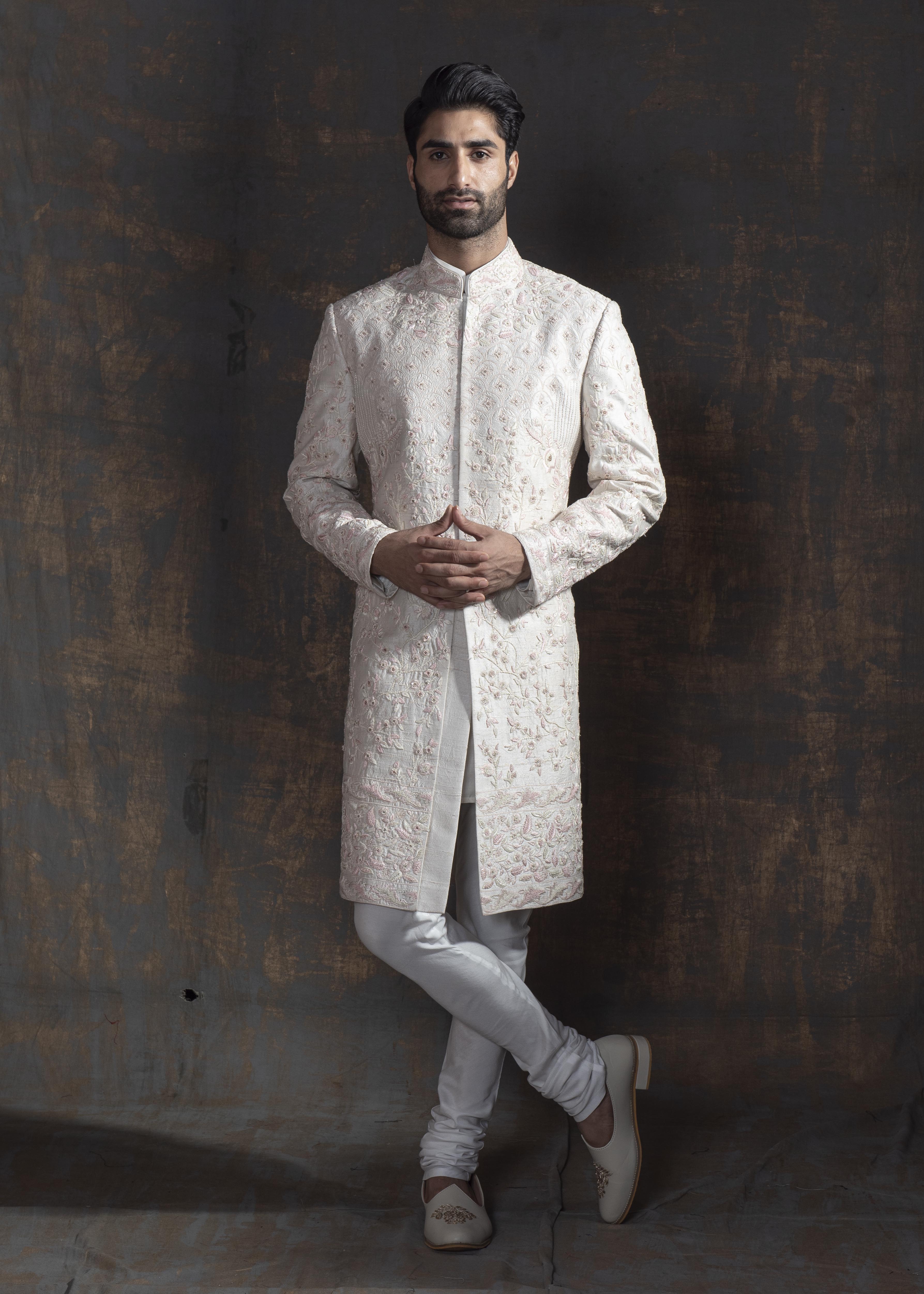 Ivory raw silk sherwani with all over light pink coloured hand embroidery. Paired up with off white kurta and chooridaar and an ivory stole with the sherwani's embroidery as the border.