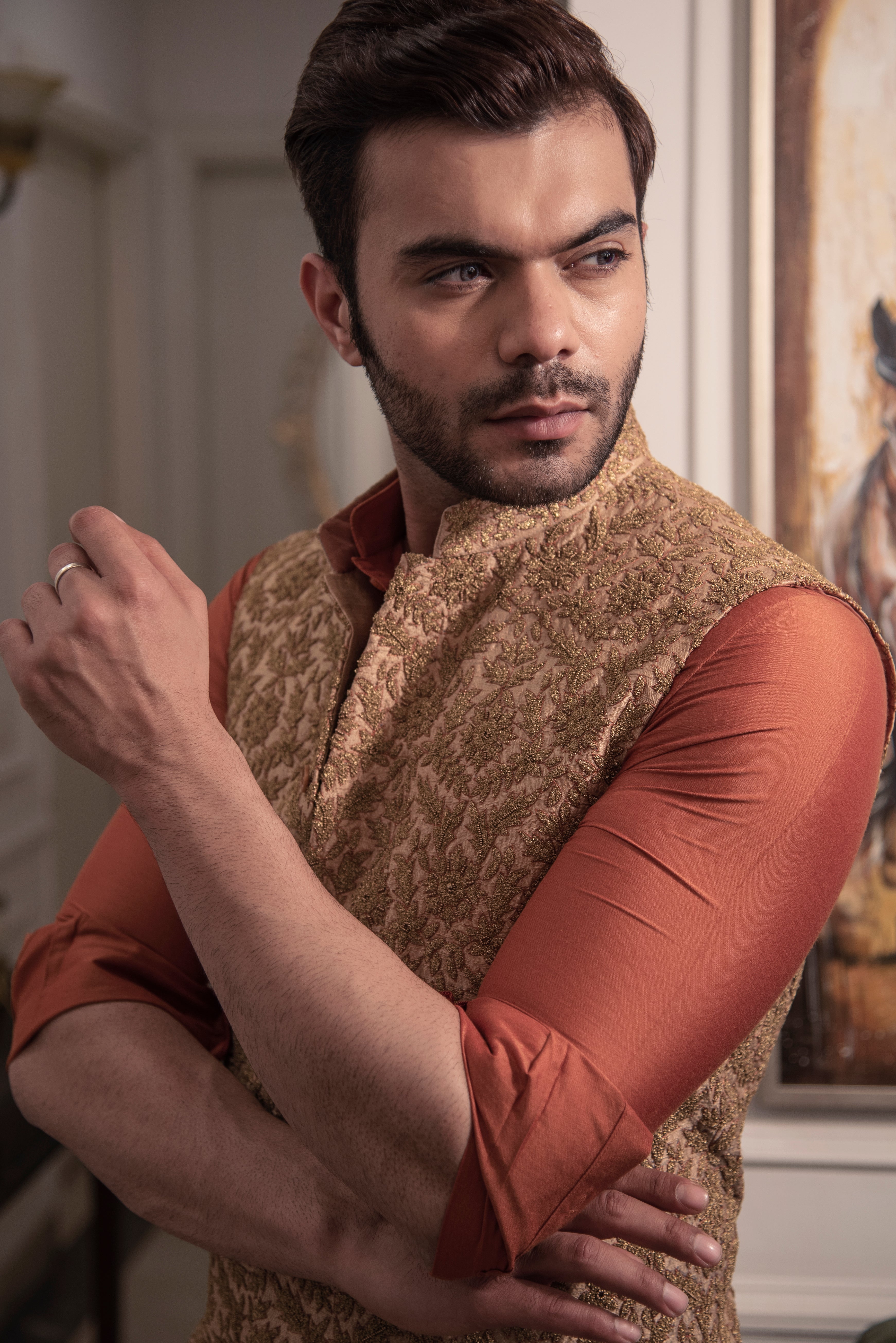 Gold heavy embroidered nehru jacket with rust coloured kurta and off white pajama.