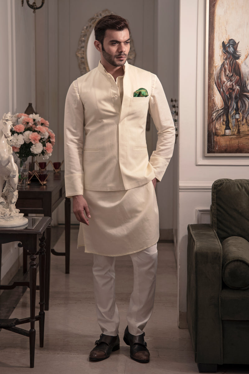 Cream coloured nehru jacket with cream coloured kurta and off white pant pajama.